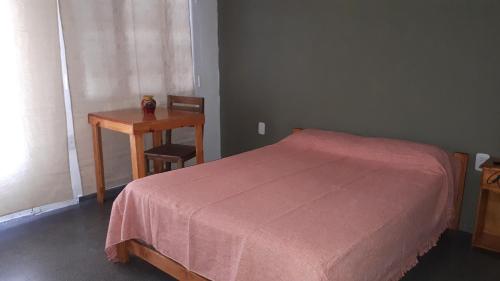 a bedroom with a bed and a table and a desk at SIGRUM Hostel in San Rafael