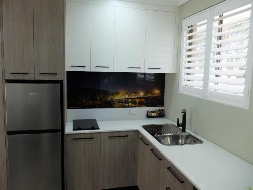 a kitchen with white cabinets and a stainless steel refrigerator at Barooga River Gums Motor Inn in Barooga