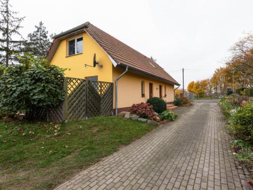 una casa gialla con recinzione e vialetto di Vacation apartment in Usedom on the Baltic Sea a Stolpe auf Usedom