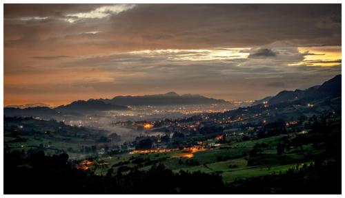a view of a city at night with the sun setting at Espectacular cabaña campestre con granja in Zipaquirá