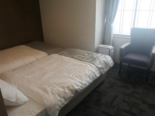 a bedroom with a bed and a chair and a window at New Tomakomai Prince Hotel NAGOMI in Tomakomai