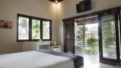 a bedroom with a bed and windows and a television at Puri Rinjani Bungalows in Kuta Lombok