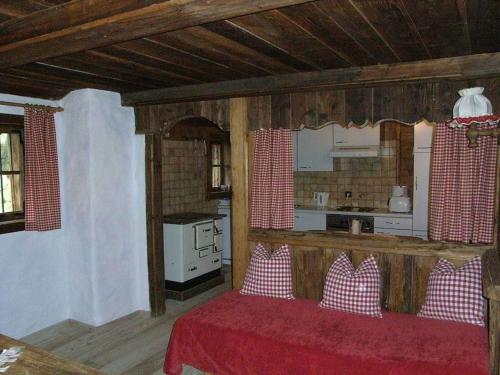 ein Wohnzimmer mit einem roten Bett und eine Küche in der Unterkunft Hütte - Ferienhaus Bischoferhütte für 2-10 Personen in Alpbach