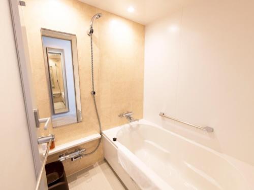 a white bath tub in a bathroom with a mirror at Kawagoe Tobu Hotel in Kawagoe