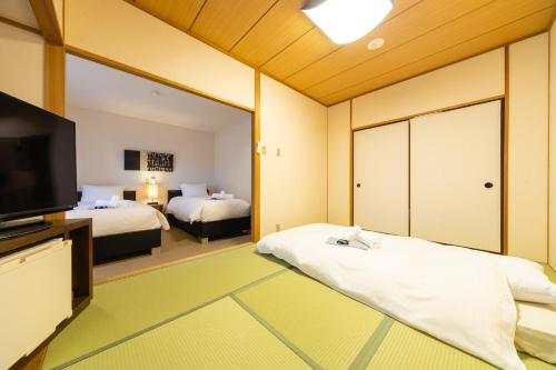 a bedroom with two beds and a large mirror at Phoenix Hotel by Hakuba Hospitality Group in Hakuba
