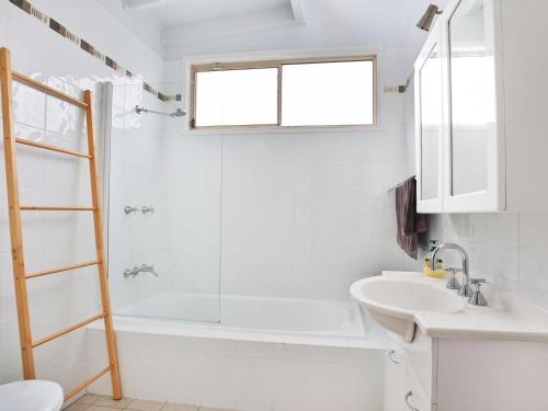 Un baño blanco con ducha y lavabo. en The Deckhouse I Pet Friendly I 2 Mins to Beach, en Culburra Beach