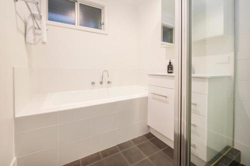 a white bathroom with a tub and a shower at Eagle Bay Beach House in Dunsborough