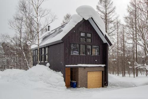 a building with a snow covered roof in the snow at Kitsune House with Sauna close to Rusutsu Ski Resort in Rusutsu