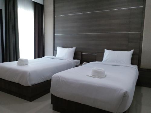 2 Betten in einem Hotelzimmer mit weißer Bettwäsche in der Unterkunft Areena Hotel Phitsanulok in Phitsanulok