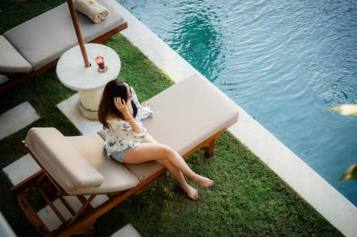 a woman sitting on a bench next to the water at Villa Perle an Idyllic Luxury Retreat in Karangasem