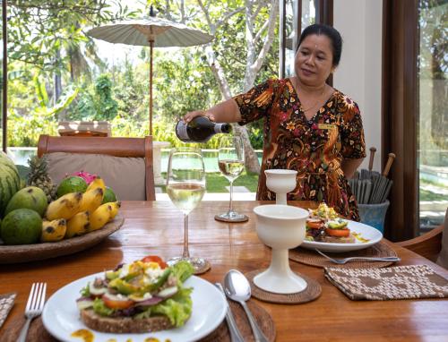 a woman pouring a glass of wine at a table at Villa Perle an Idyllic Luxury Retreat in Karangasem