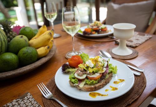 a table with a plate of food and glasses of wine at Villa Perle an Idyllic Luxury Retreat in Karangasem