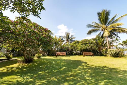 two benches in a park with palm trees at Villa Perle an Idyllic Luxury Retreat in Karangasem