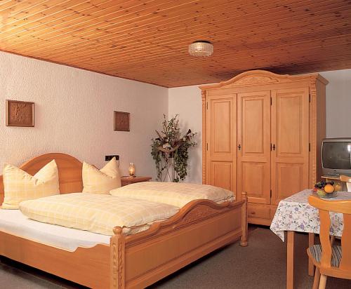 a bedroom with a wooden bed and a tv at Zur Alten Dampfsäge - Gasthaus-Pension Weber in Lindberg