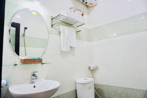Baño blanco con lavabo y espejo en Tehana Beach Hotel Da Nang, en Da Nang