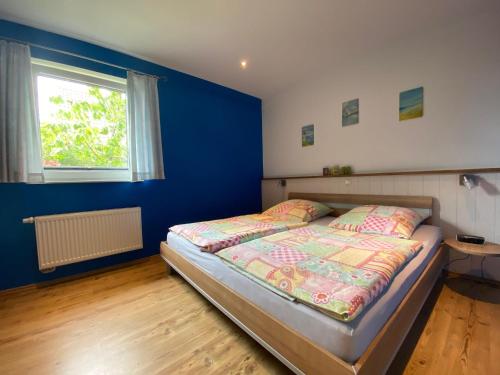 a bedroom with a bed and a blue wall at Ferienhaus-Maxe-Wohnung-Joona in Wulfen auf Fehmarn