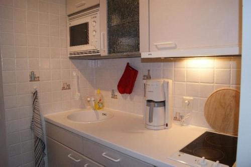 eine weiße Küche mit einer Spüle und einer Mikrowelle in der Unterkunft SONNENSCHEIN  in Burgtiefe auf Fehmarn 