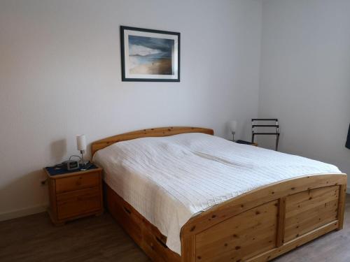 ein Schlafzimmer mit einem Holzbett und einem Bild an der Wand in der Unterkunft Bi de Kark in Sankt Peter-Ording