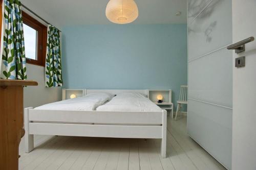 Un dormitorio con una cama blanca con una pared azul. en Sylt-Bungalow, en Westerland