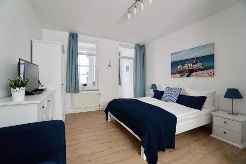 ein weißes Schlafzimmer mit einem Bett und einem TV in der Unterkunft Granitz 09, Appartement 9 (bis 2 Personen) in Ostseebad Sellin