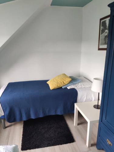 a bedroom with a bed with a blue blanket and a table at La petite maison du coin de Loguivy de la Mer in Ploubazlanec