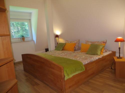 クヴェードリンブルクにあるWeisses-Haus-am-Kurpark-Fewo-Waldblickのベッドルーム1室(木製ベッド1台、緑とオレンジの枕付)