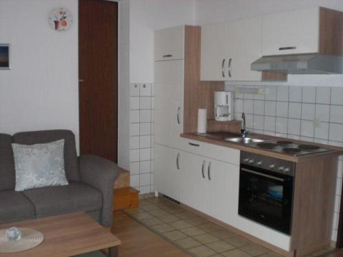 a living room with a couch and a kitchen at Ferienwohnung-Marita in Carolinensiel