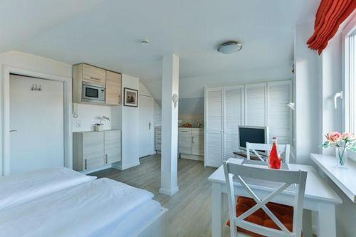 Dieses weiße Zimmer verfügt über ein Bett, einen Tisch und eine Küche. in der Unterkunft Haus Brönshoog, Appartement 11 in strandnaher Lage in Wenningstedt-Braderup