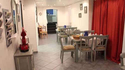 - une salle à manger avec des tables, des chaises et un rideau rouge dans l'établissement Kapitaenshaus-Lassen-Zimmer-Amistad, à Westerland