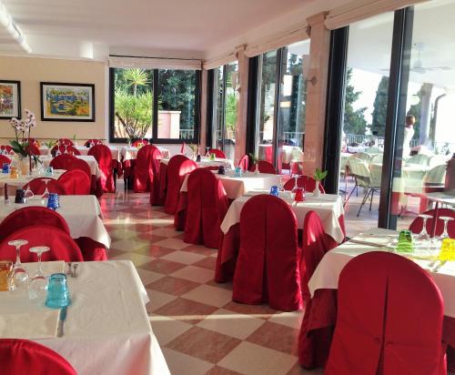 ein Esszimmer mit Tischen, roten Stühlen und einem Tisch in der Unterkunft Hotel Panorama Ristorante ***S in Torri del Benaco