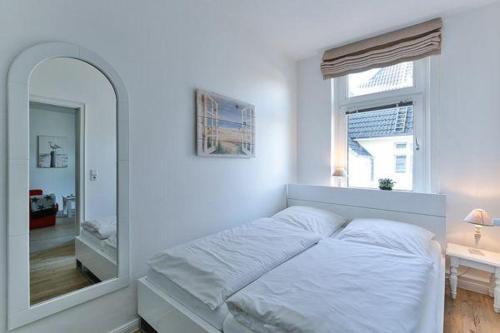 - une chambre blanche avec un lit et un miroir dans l'établissement App-7-in-strandnaher-Lage-Baederstil-Villa-in-Wenningstedt-Sylt, à Wenningstedt