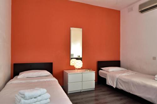 two beds in a room with orange walls at City Living Suites TK1 Rm 2 in St. Julianʼs