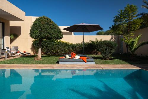 a swimming pool with an umbrella next to a house at Sirayane Boutique Hotel & Spa Marrakech in Marrakesh