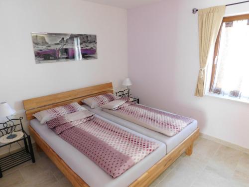 Schlafzimmer mit einem Bett mit rosa Bettwäsche und einem Fenster in der Unterkunft Ferienwohnung am Rosengarten in Füssen
