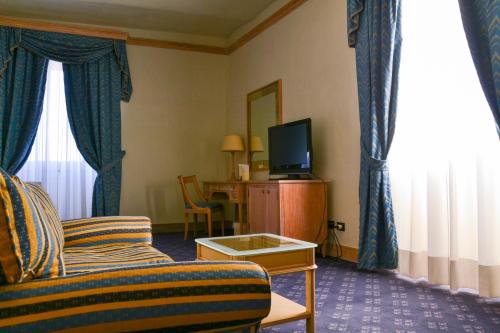 a hotel room with a couch and a television at Hotel De La Ville in Civitavecchia