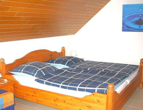 ein Schlafzimmer mit einem Holzbett mit blauen Kissen in der Unterkunft Goldene-Linie 4 Deichblick in Wangerland