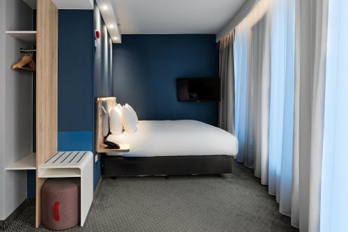 a hotel room with a bed and blue walls at Holiday Inn Express - Warsaw - The HUB by IHG in Warsaw