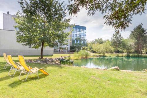 a group of chairs sitting in the grass next to a pond at Parkhotel Viktoria in Velten