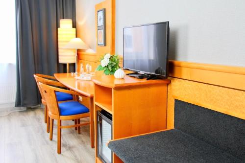 um quarto de hotel com uma secretária e uma televisão em Parkhotel Viktoria em Velten