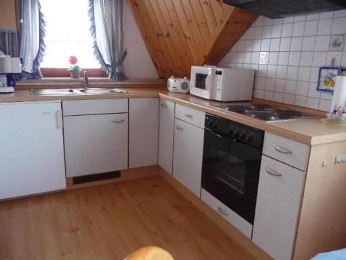 a kitchen with white cabinets and a stove and a microwave at Ferienwohnung-Nr-1 in Vöhrenbach