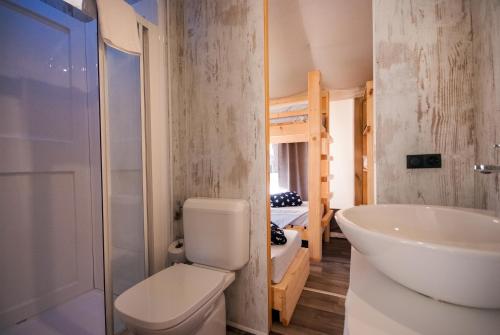 a bathroom with a toilet and a sink and a bunk bed at Camping Europa in Capoliveri