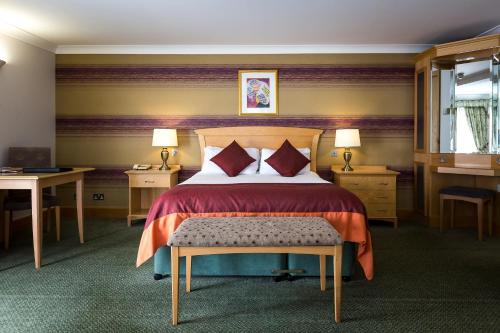 a bedroom with a bed and two tables and a window at Hellidon Lakes Hotel in Daventry