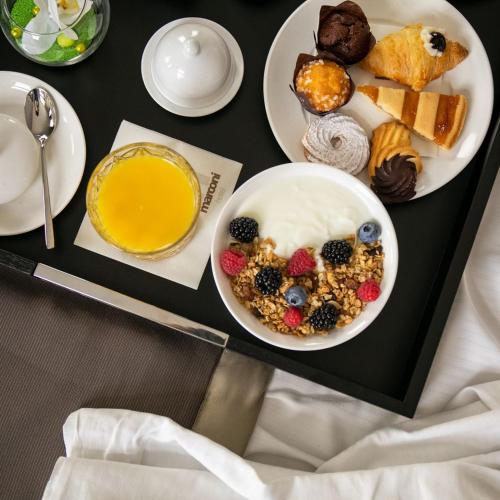 a table with two plates of breakfast foods and a bowl of cereal at Marconi Hotel in Rende