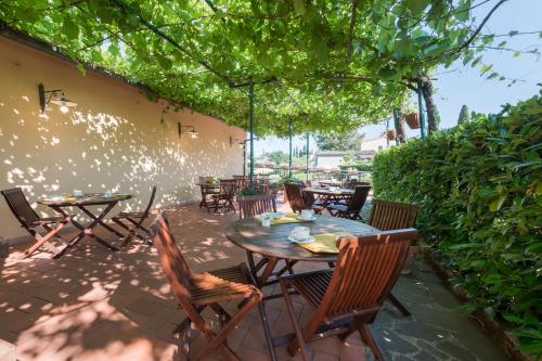 a patio with tables and chairs under a tree at Hotel San Michele in San Gimignano