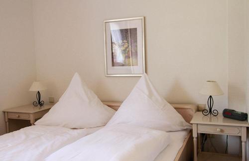 ヴェスターラントにあるHaus-Meisennest-Wohnung-Meiseのベッドルーム1室(白いシーツとテーブル2台付きのベッド2台付)