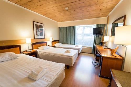 Habitación de hotel con 2 camas y escritorio en Budget Hotel Raahe en Raahe