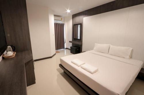 a bedroom with a large white bed with white pillows at Fortune Surin Hotel in Surin