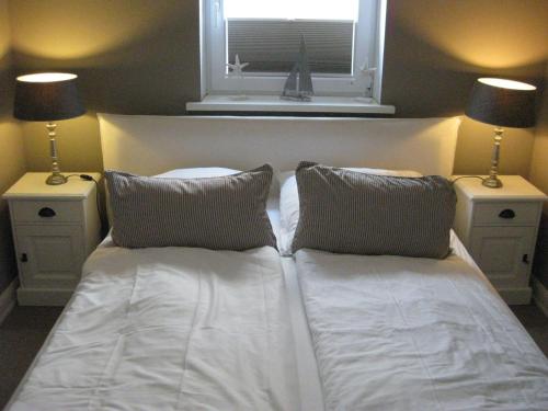 ヴェスターラントにあるHaus-Quisisana-App-6の白いベッド(枕2つ付)、窓が備わります。