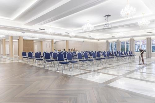 a room with blue chairs and a person standing in the middle at BURSZTYN - BERNSTEIN SPA & Wellness in Dąbki