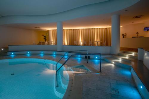 a large swimming pool with blue lights in a building at El Faro Hotel & Spa in Porto Conte